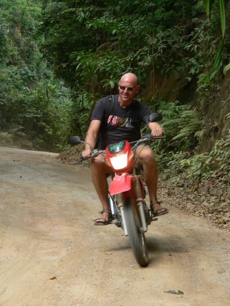 Daniel riding a motorbike on a jungle road in Thailand
